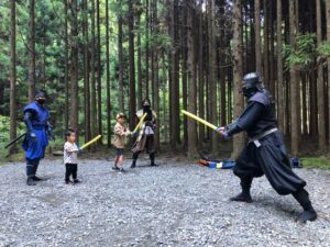 リアルな扮装の忍者と幼児が木刀を構え一対一で向かい合っている。